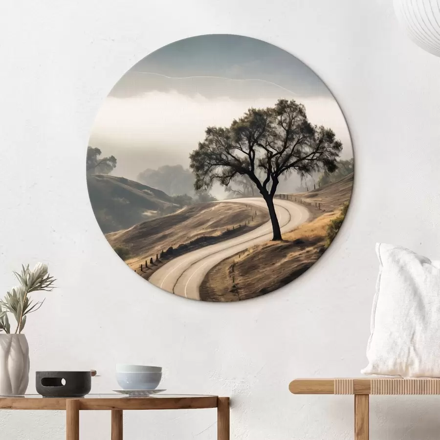 Wandbilder Eine kurvenreiche Straße durch sanfte Hügel mit einem Baum im Vordergrund, im Hintergrund Nebel und Berge r46288
